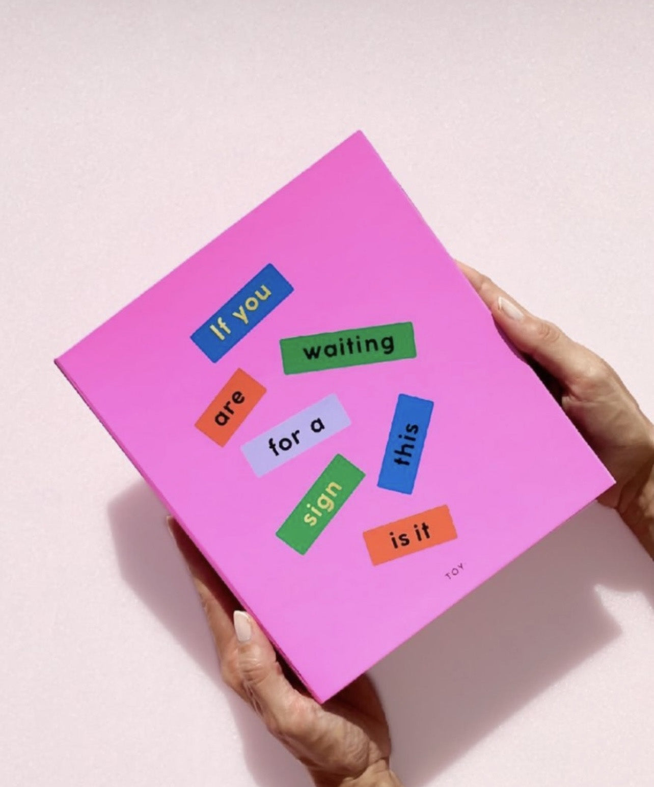 Una agenda cerrada sujetada por un par de manos. 