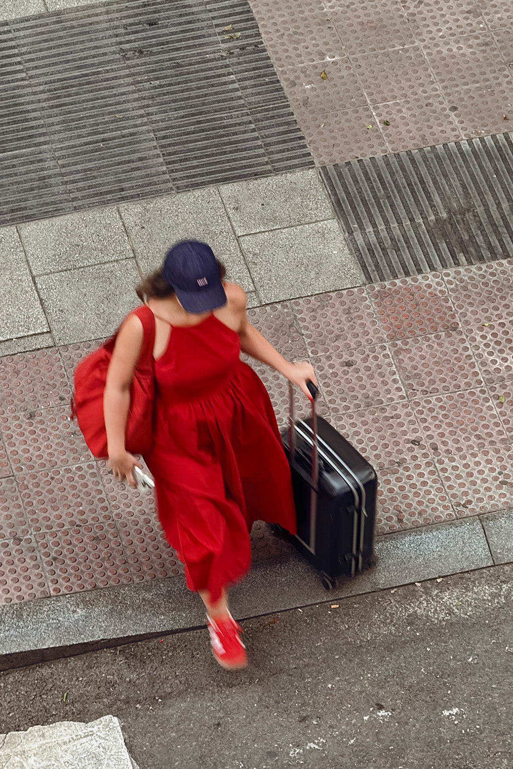 Una mujer cruza una pista con una maleta de ruedas.